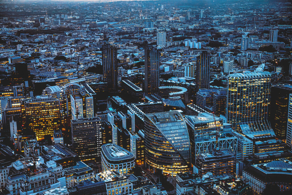 Aerial panoramic view of The City of London cityscape skyline with metropole financial district modern skyscrapers after sunset on night with illuminated buildings and cloudy sky in London, UK