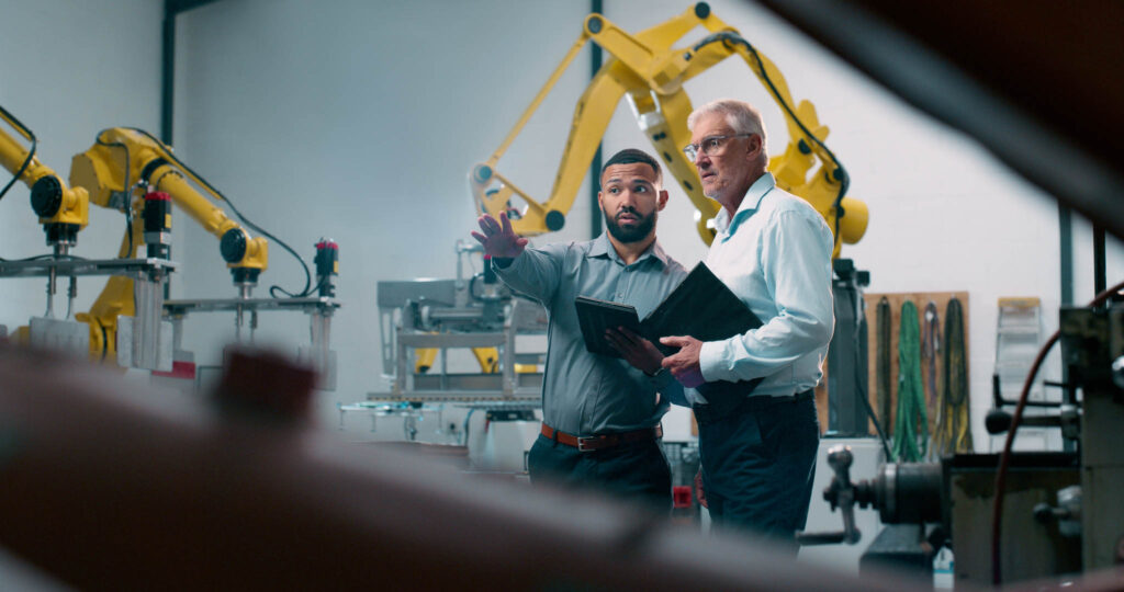 Robotics, people and engineer tablet with industrial collaboration and planning in warehouse. Factory, engineering and futuristic work of manufacturing management with discussion for cnc automation.